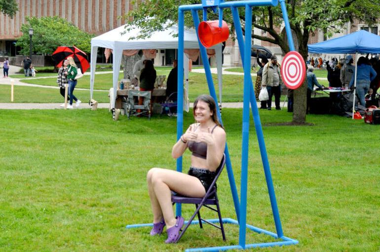 A female student gives a thumbs up after a ball hit a bucket that doused her with water